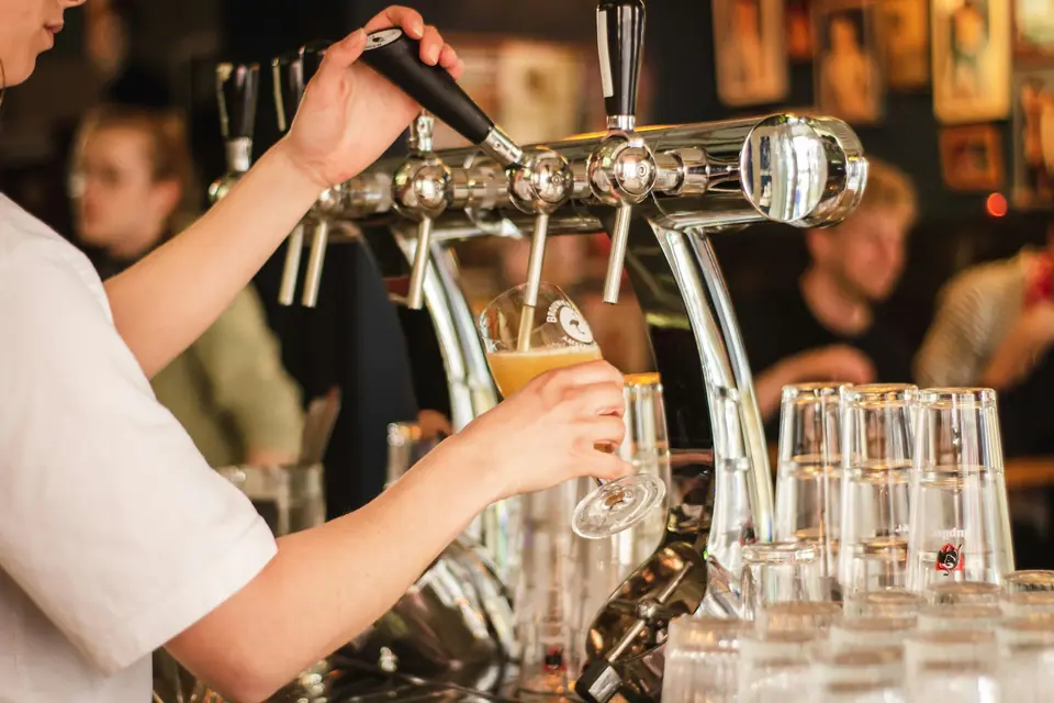 Un barman tire une pression au comptoir d'un bar plein