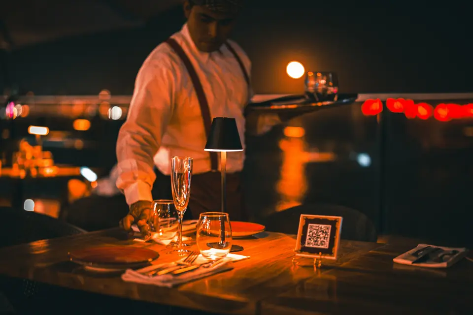 Un serveur dresse une table dans un restaurant, le soir
